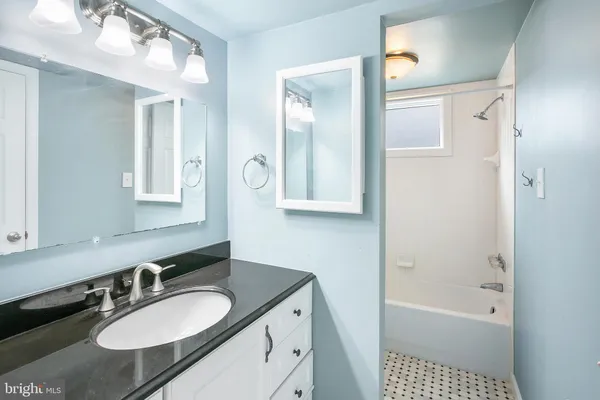 a bathroom with a granite countertop sink mirror and a bathtub