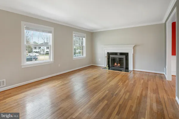 a view of an empty room with wooden floor fireplace and a window