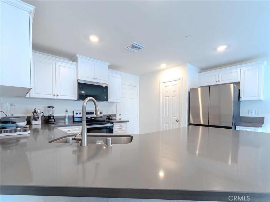 25602 Pne Rdg Road Homeland, CA 92548 - Photo 9 of 35 a kitchen with stainless steel appliances granite countertop a stove a refrigerator a sink a oven and white cabinets