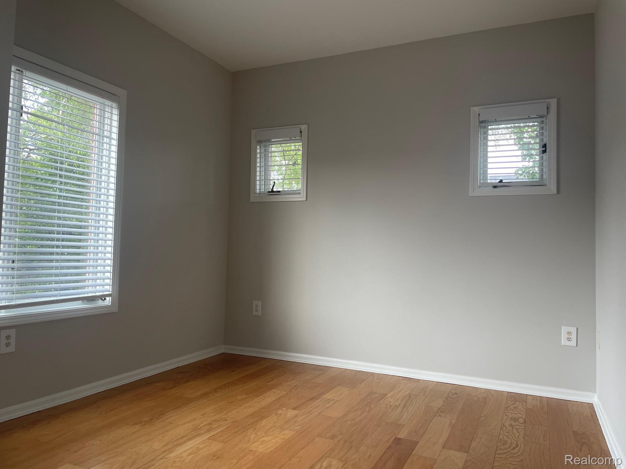 2727 East Maple Road Birmingham, MI 48009 - Photo 26 of 29 Wood-finish flooring, light-toned walls, multiple windows with blinds, and white trim molding