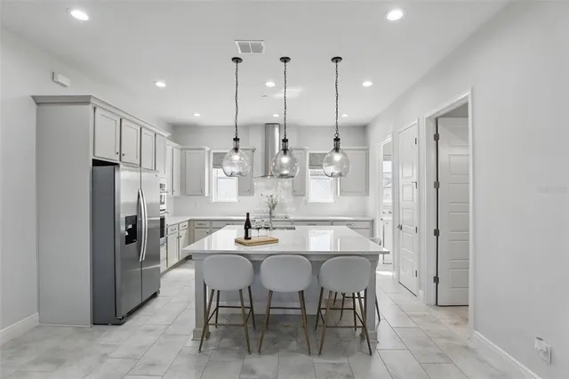 a kitchen with stainless steel appliances kitchen island granite countertop a refrigerator and a dining table