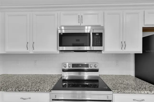 a kitchen with granite countertop white cabinets and appliances