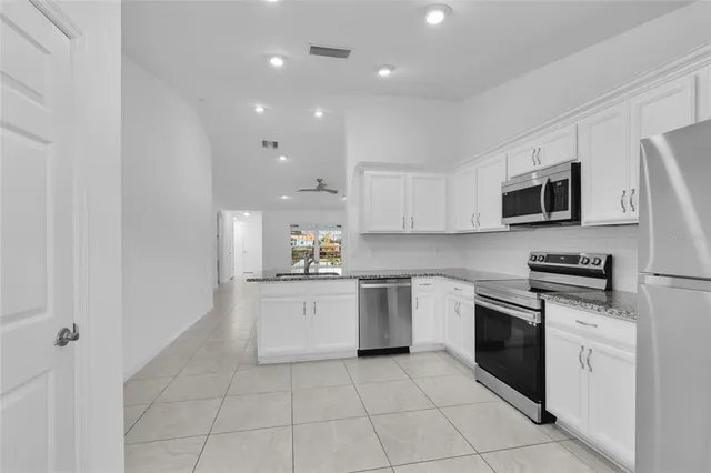 a kitchen with granite countertop white cabinets stainless steel appliances and a sink