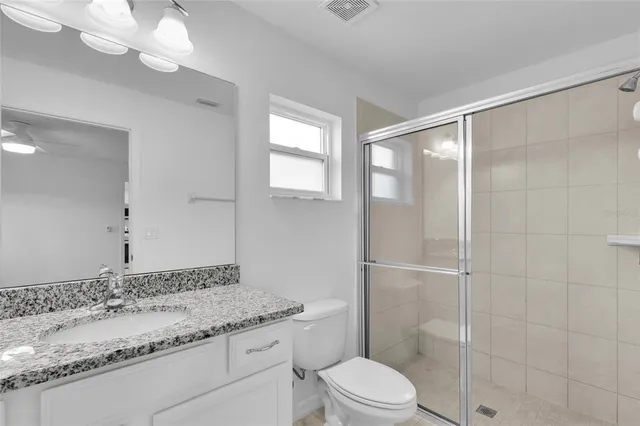 a bathroom with a granite countertop sink a toilet and shower