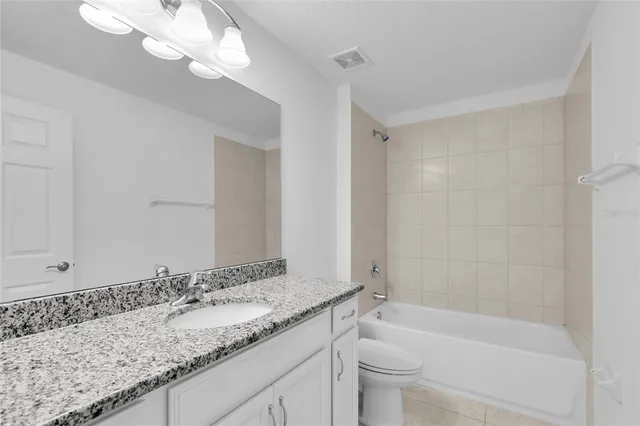 a bathroom with a granite countertop sink a toilet and bathtub