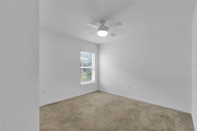 an empty room with a window and a fan