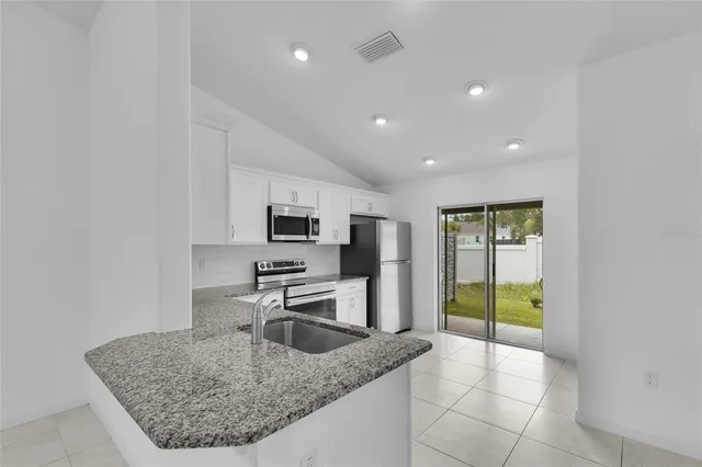 a kitchen with stainless steel appliances granite countertop a sink a stove and a refrigerator