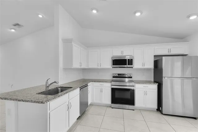 a kitchen with granite countertop a sink stove and refrigerator