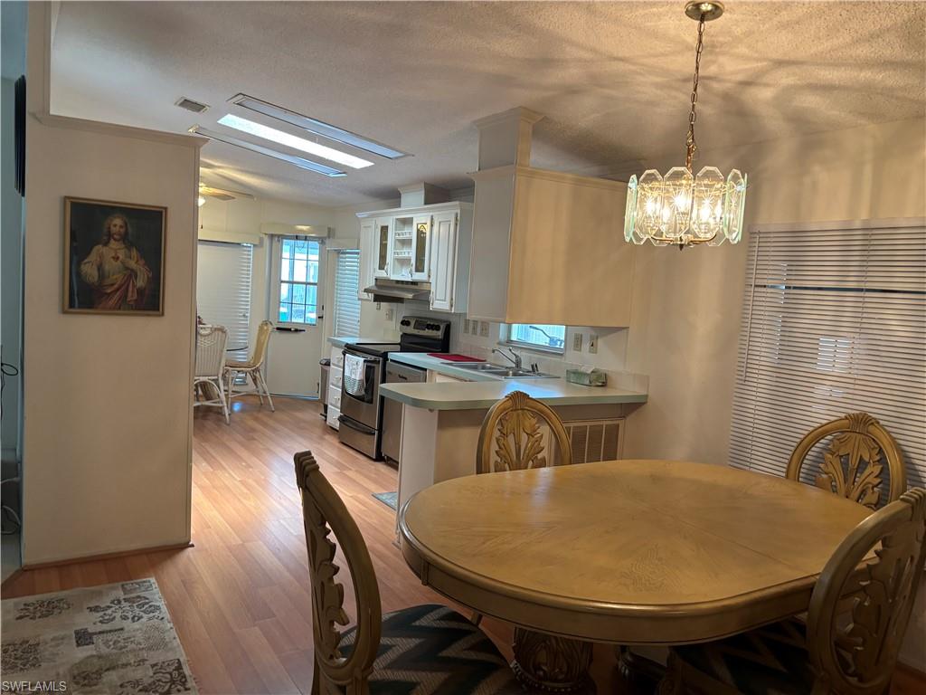 49 Turquoise Avenue, Unit 49T Naples, FL 34114 - Photo 14 of 29 a dining room with furniture a chandelier and wooden floor