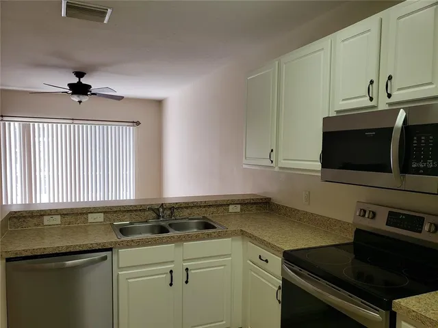 a kitchen with stainless steel appliances white cabinets and a refrigerator