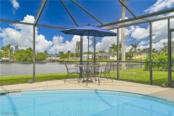 a view of a swimming pool with a table and chairs under an umbrella