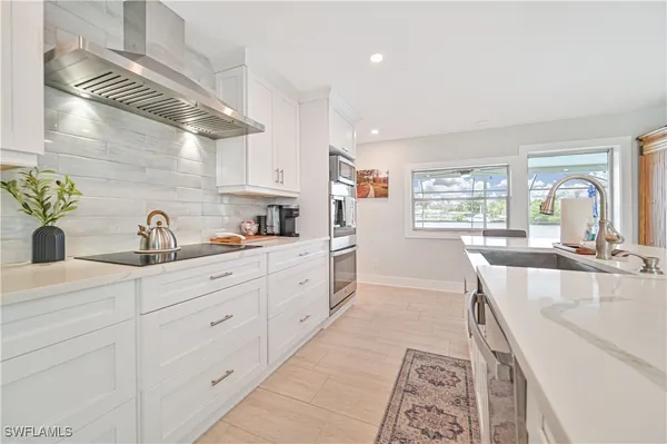 a large kitchen with kitchen island white cabinets and a sink