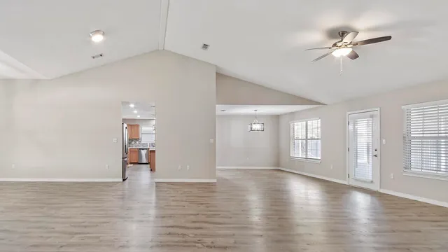 a view of an empty room with a window and wooden floor