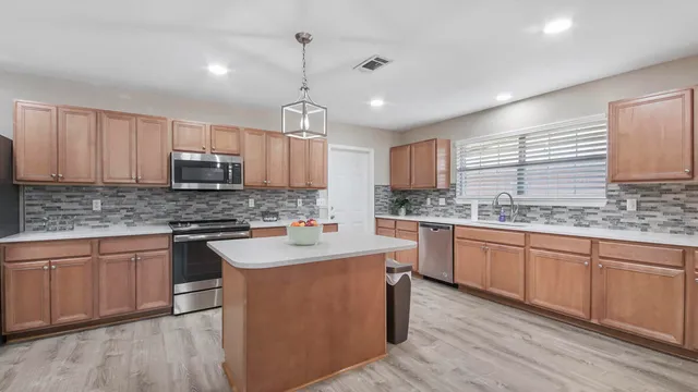 a kitchen with kitchen island granite countertop stainless steel appliances a sink cabinets a counter top space and a center island