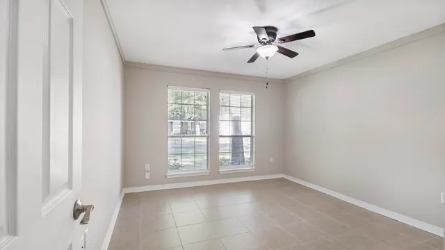 an empty room with ceiling fan and windows