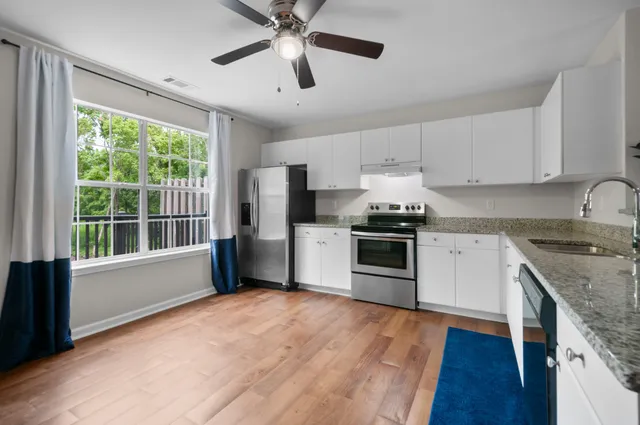 a kitchen with granite countertop a stove top oven a sink and white cabinets