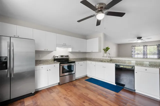a kitchen with granite countertop stainless steel appliances a sink and a refrigerator