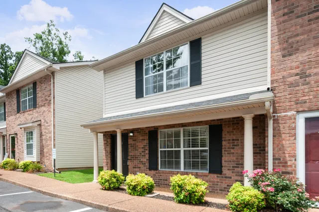 front view of a brick house with a large window and potted plants