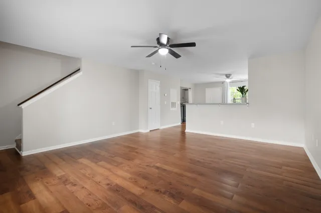 a view of an empty room with wooden floor and a ceiling fan