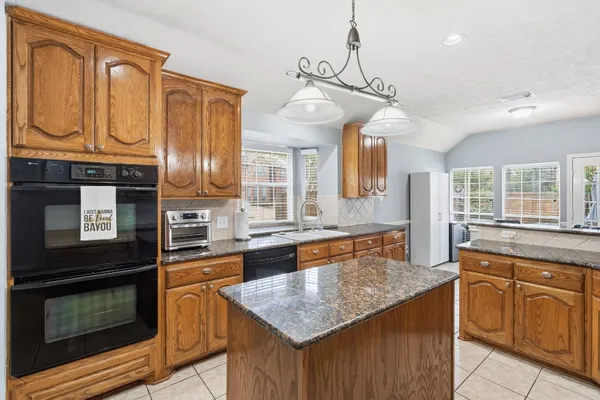 a kitchen with granite countertop wooden cabinets a dining table and chairs