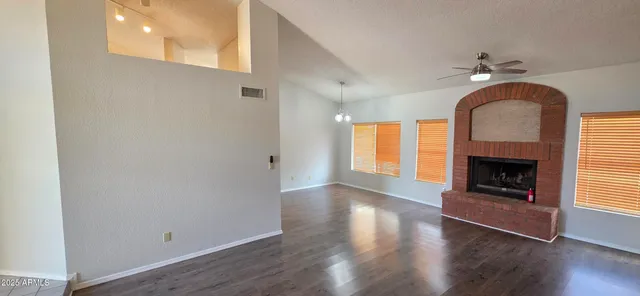 an empty room with wooden floor fireplace and windows