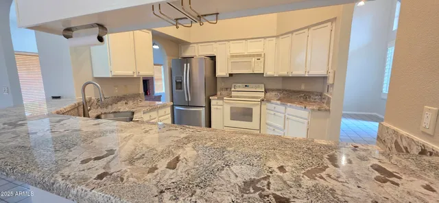 a kitchen with granite countertop a refrigerator and a sink