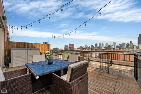 a roof deck with a dining table and chairs with wooden floor