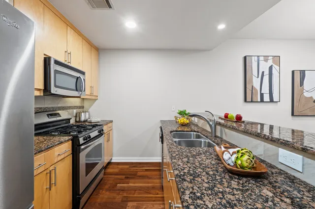 a kitchen with stainless steel appliances granite countertop a stove a sink and a microwave