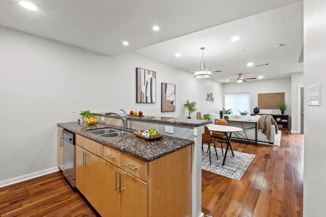 a kitchen with stainless steel appliances granite countertop a stove a sink a refrigerator and chairs