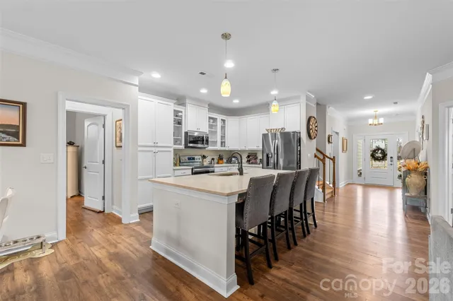 a kitchen with stainless steel appliances a sink a stove oven a refrigerator with white cabinets and wooden floor