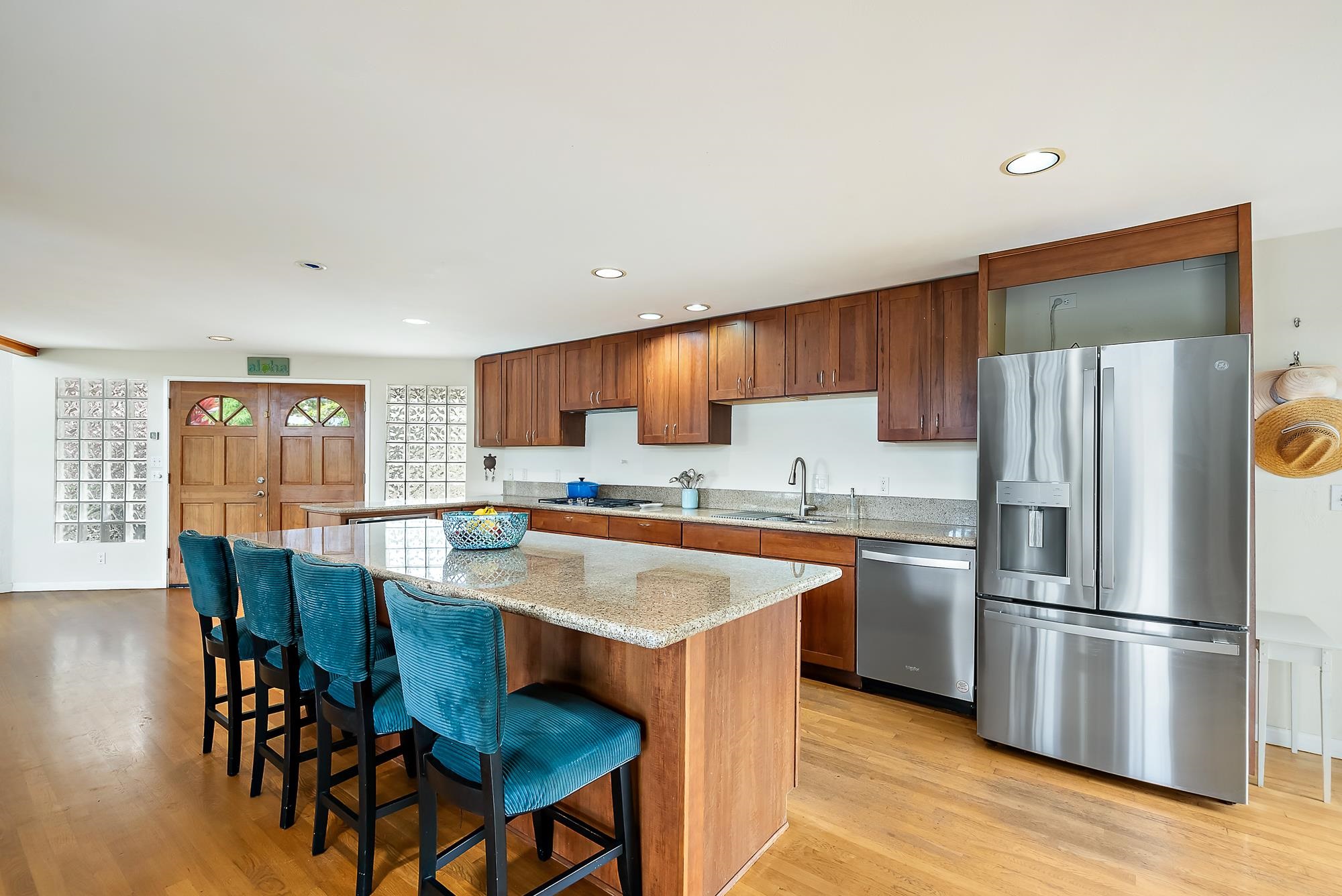 20 Pea Place Kula, HI 96790 - Photo 9 of 49 a kitchen with stainless steel appliances granite countertop a stove a refrigerator a microwave a dining table and chairs with wooden floor