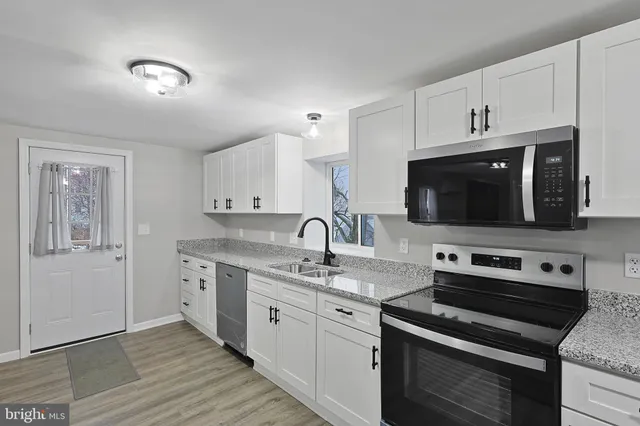 a kitchen with stainless steel appliances granite countertop a stove a sink and a microwave