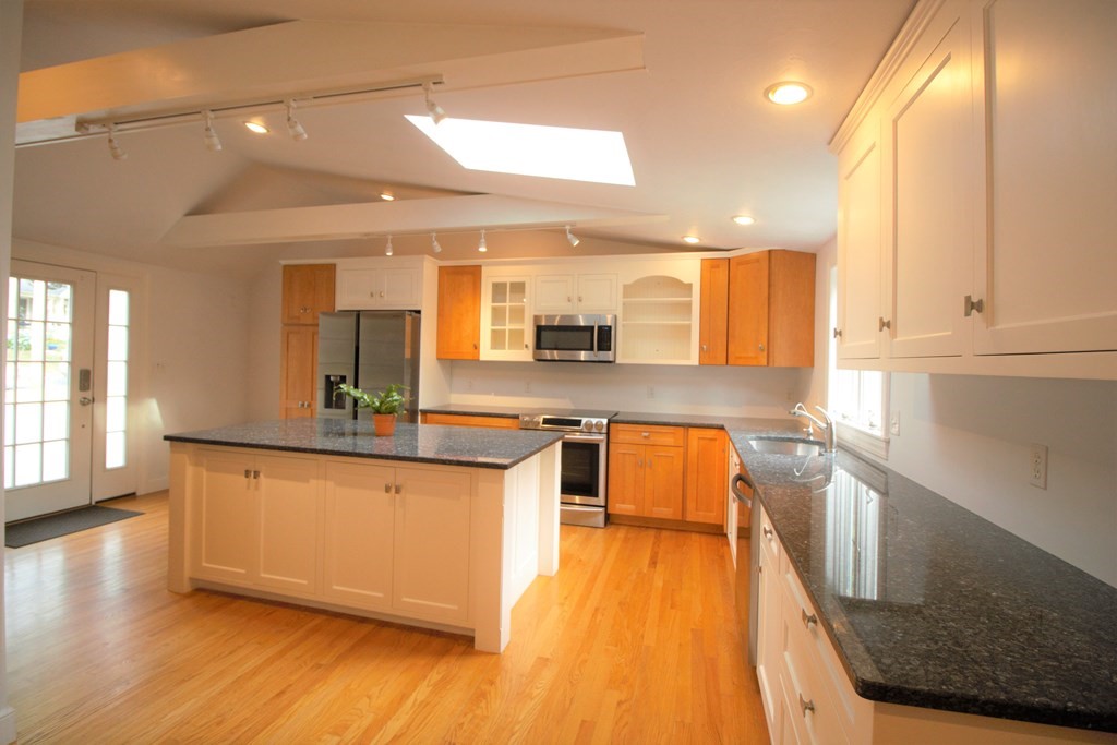 a large kitchen with stainless steel appliances a large window a sink and a counter top space