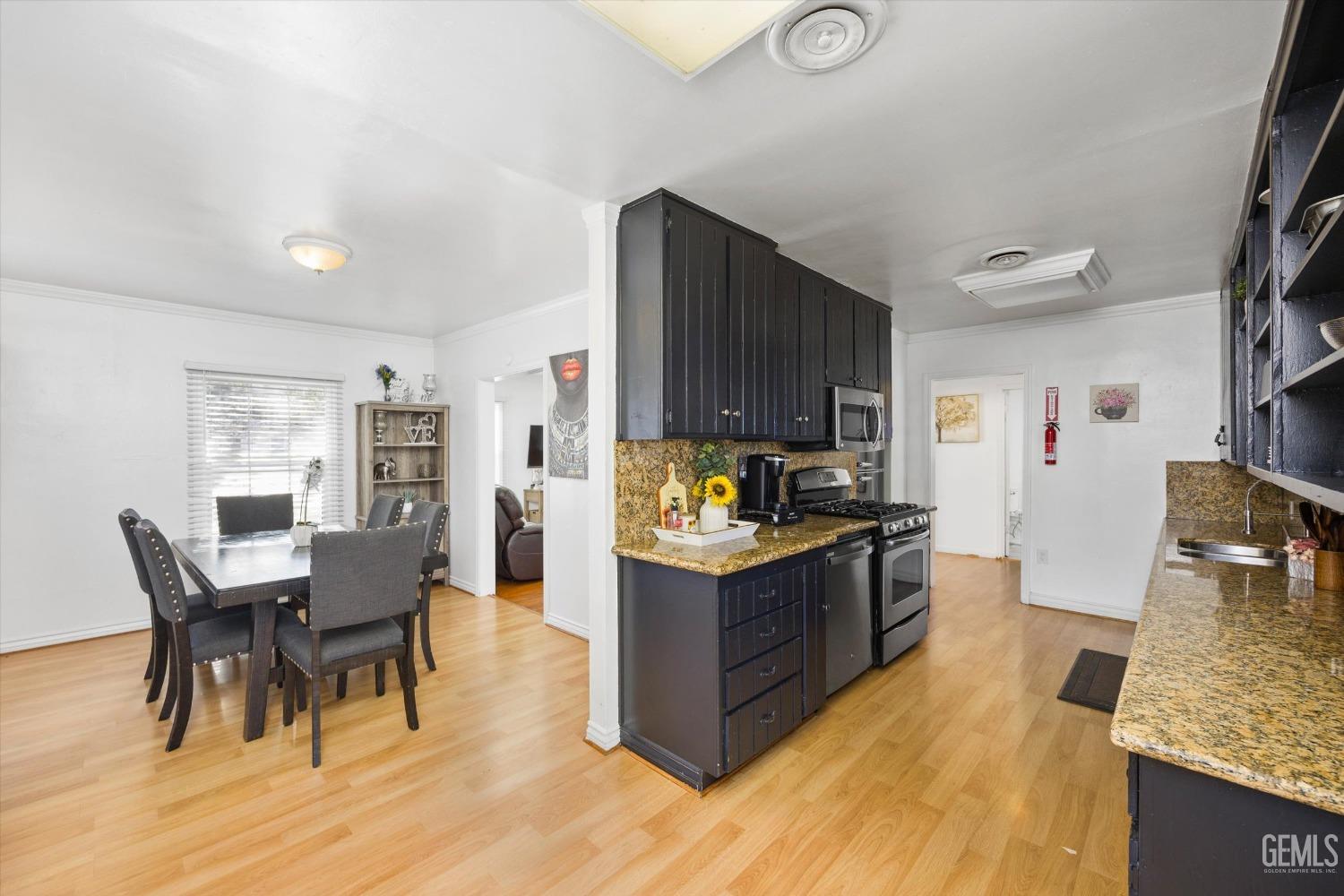 Undisclosed Address Bakersfield, CA 93312 - Photo 10 of 35 a kitchen with stainless steel appliances granite countertop a stove top oven a sink dishwasher a dining table and chairs with wooden floor
