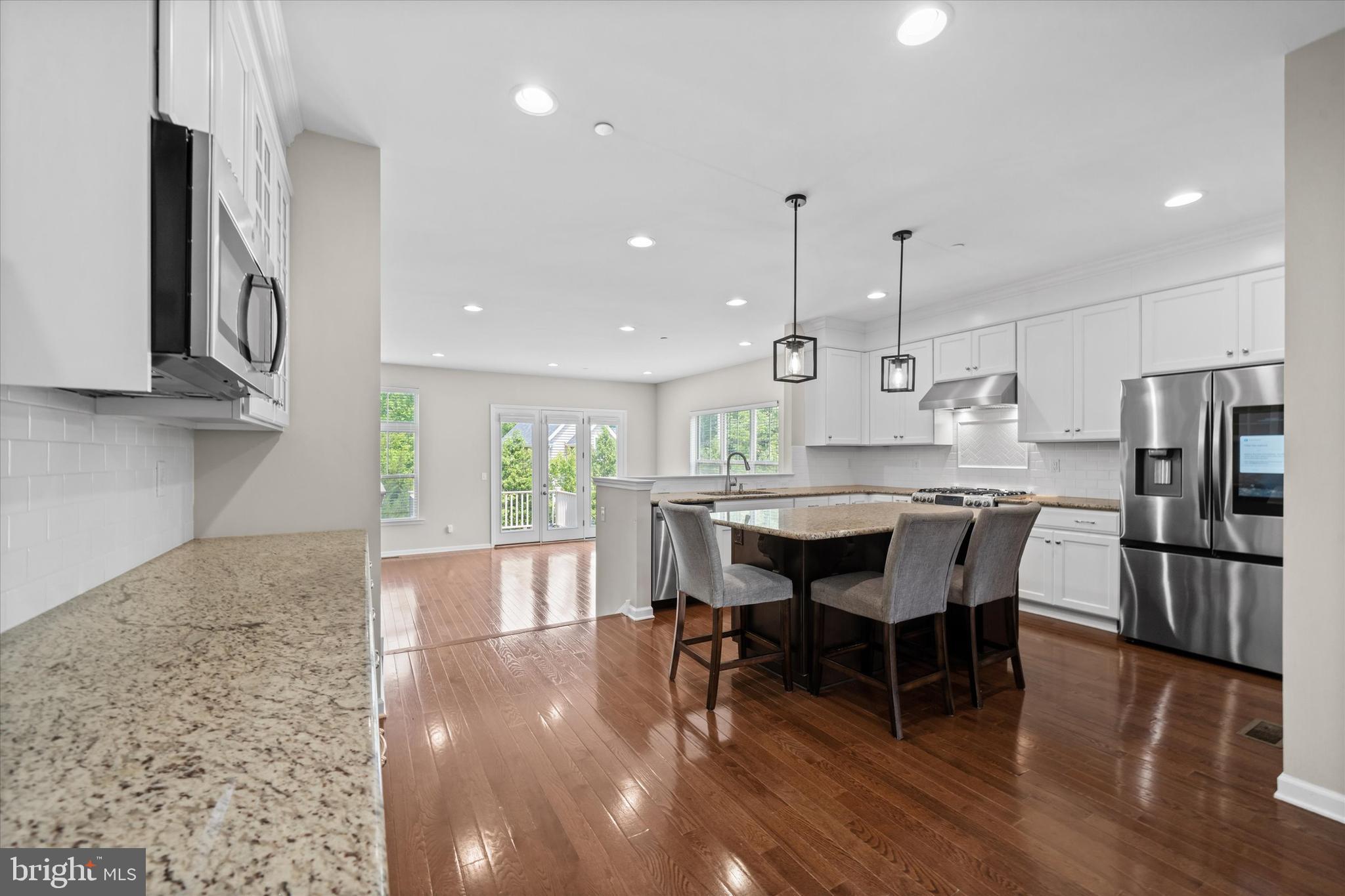 10 Chasmere Drive Kennett Square, PA 19348 - Photo 8 of 49 a kitchen with stainless steel appliances granite countertop a stove a refrigerator a kitchen island a dining table and chairs with wooden floor