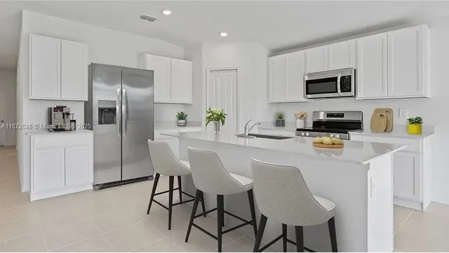 a kitchen with stainless steel appliances a refrigerator a stove a sink a dining table and chairs