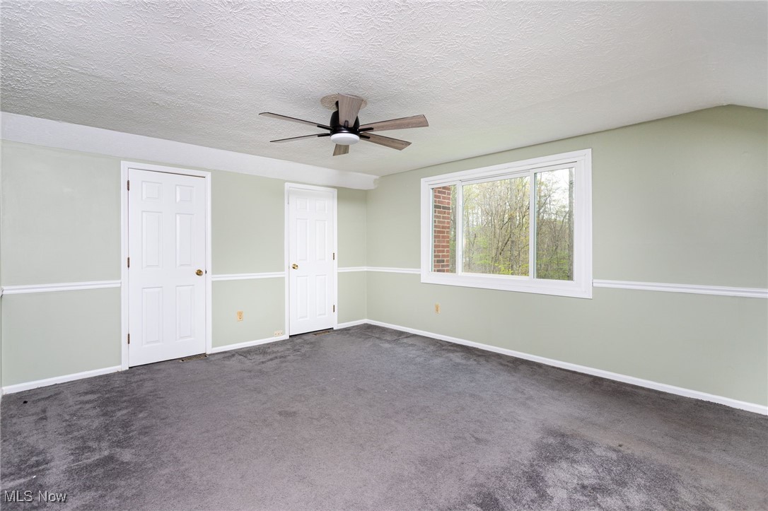 14566 West Ridge Road Novelty, OH 44072 - Photo 29 of 49 Empty room featuring baseboards, dark carpet, ceiling fan, and a textured ceiling