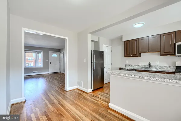 a kitchen with stainless steel appliances granite countertop a refrigerator stove top oven and sink with wooden floor