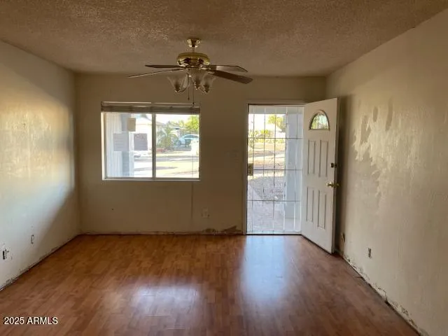 a view of an empty room with wooden floor and a window