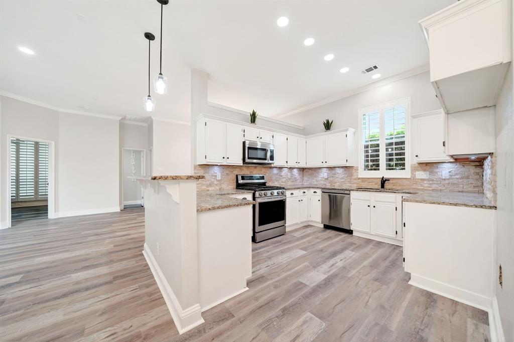 5618 Allen Lane Rowlett, TX 75088 - Photo 8 of 35 a kitchen with kitchen island granite countertop a sink cabinets and wooden floor