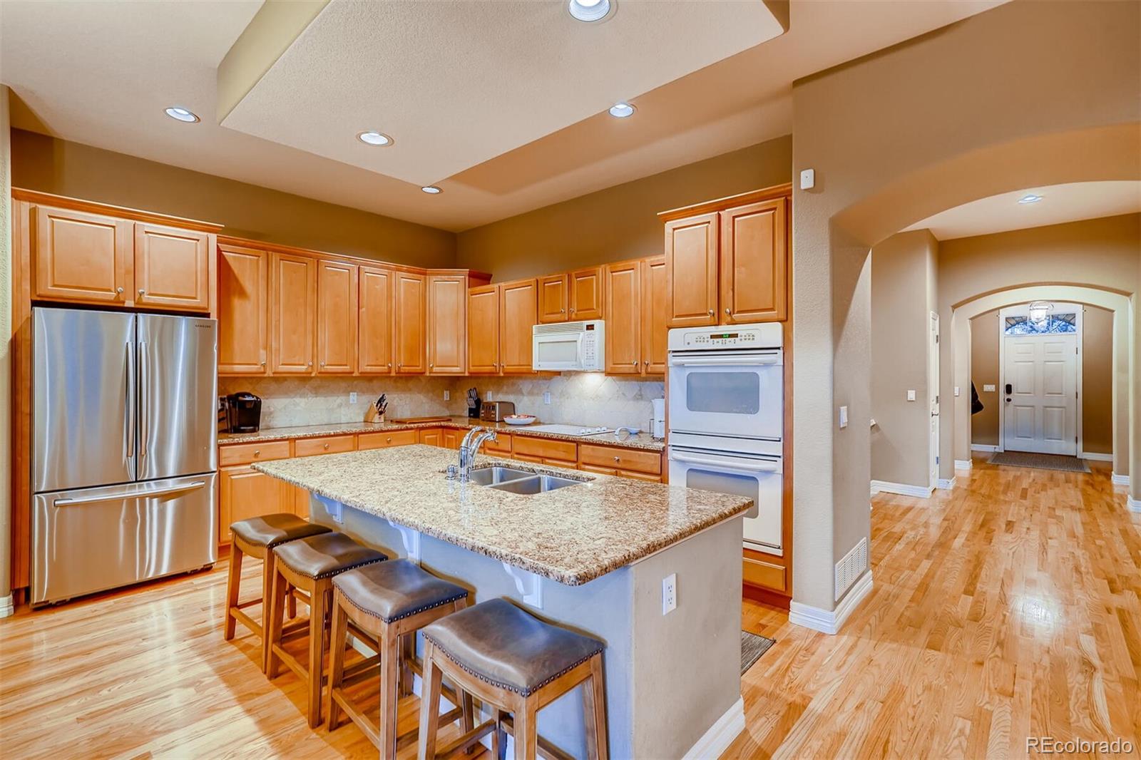 529 Uinta Way Denver, CO 80230 - Photo 5 of 40 a kitchen with granite countertop a refrigerator a sink dishwasher and wooden cabinets with wooden floor