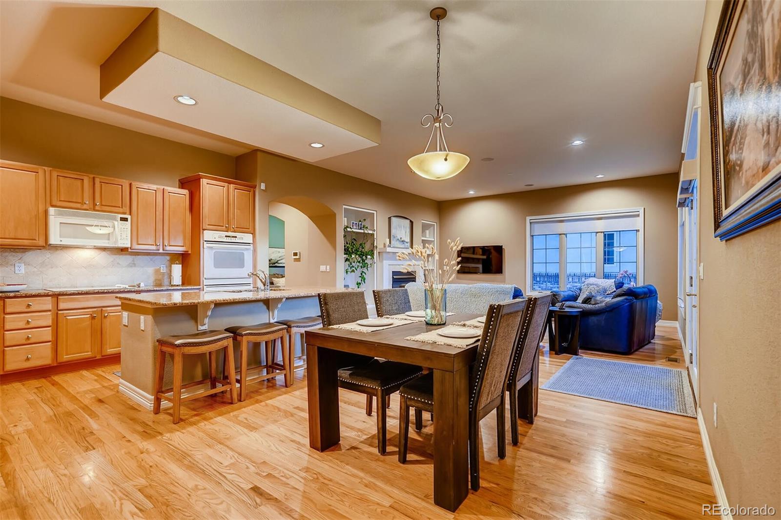 529 Uinta Way Denver, CO 80230 - Photo 9 of 40 a kitchen with stainless steel appliances granite countertop a stove a refrigerator a kitchen island a dining table and chairs with wooden floor
