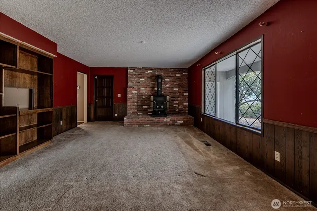 a view of an empty room with furniture and windows