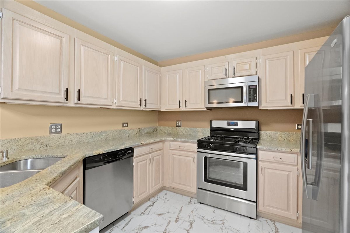 8 Hastings Lane Lincolnshire, IL 60069 - Photo 7 of 29 a kitchen with granite countertop a stove top oven microwave and cabinets