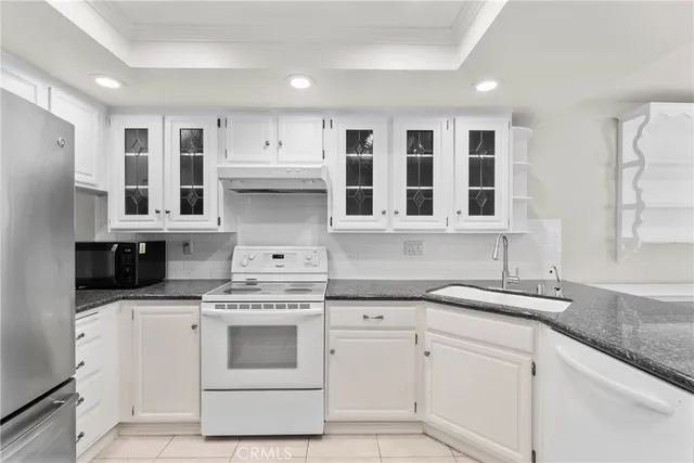 a kitchen with stainless steel appliances granite countertop white cabinets and a sink