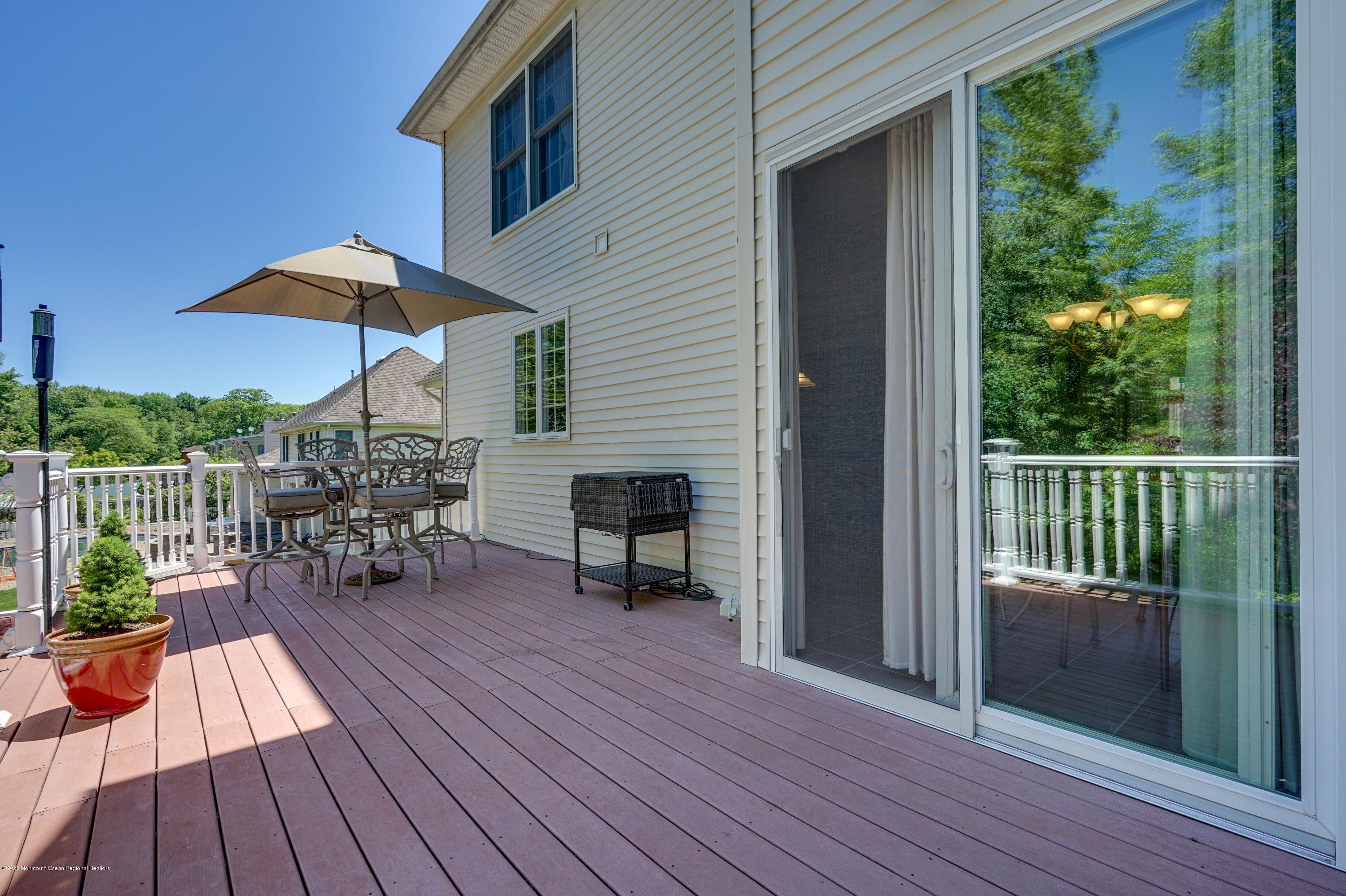 27 Northwoods Road Asbury Park, NJ 07712 - Photo 75 of 76 a view of a deck with table and chairs under an umbrella with wooden floor