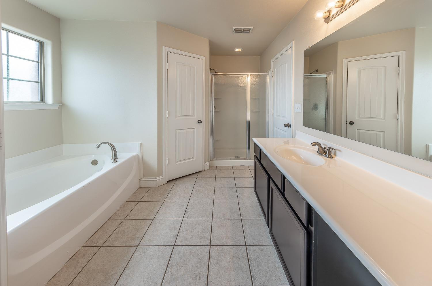 5504 110th Street Lubbock, TX 79424 - Photo 14 of 23 a spacious bathroom with a tub sink and mirror