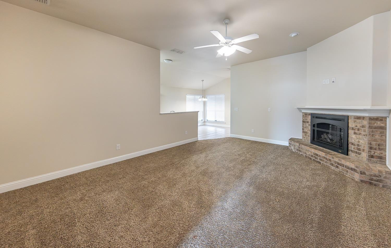 5504 110th Street Lubbock, TX 79424 - Photo 2 of 23 an empty room with fireplace and fan