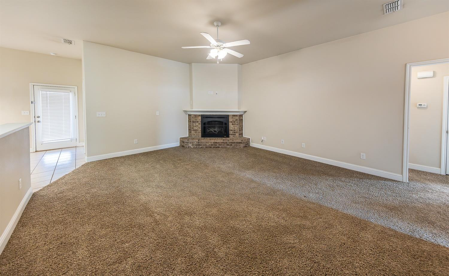 5504 110th Street Lubbock, TX 79424 - Photo 5 of 23 an empty room with a fireplace and a ceiling fan