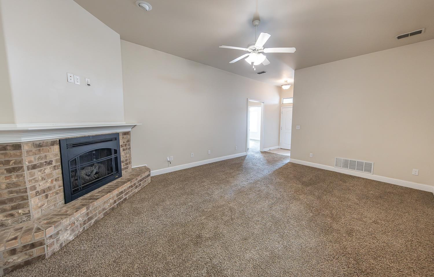 5504 110th Street Lubbock, TX 79424 - Photo 6 of 23 an empty room with a fireplace and chandelier fan